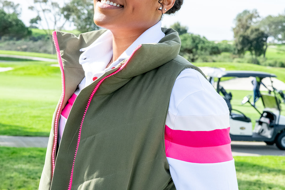Model wearing olive green twilight womens golf vest with white murray golf shirt underneath on golf course. 