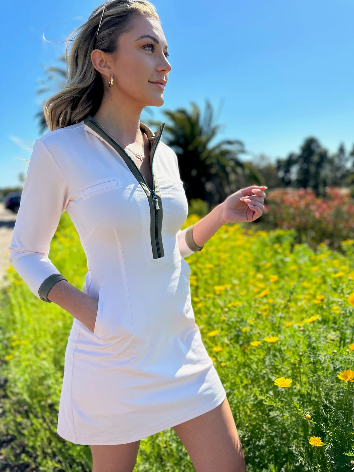 Model wearing white Dutchess womens golf dress with long sleeves with teal zipper.