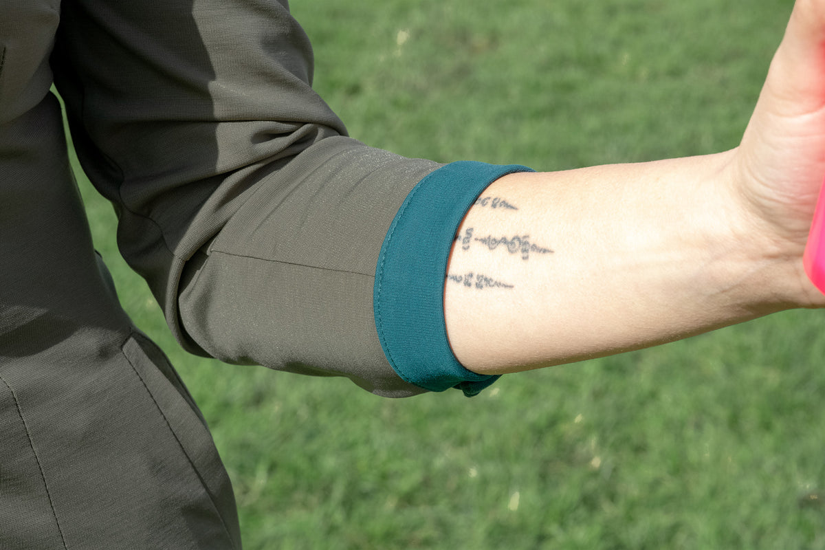 Close up of Olive Green Dutchess womens golf long sleeve dress with teal accents. 